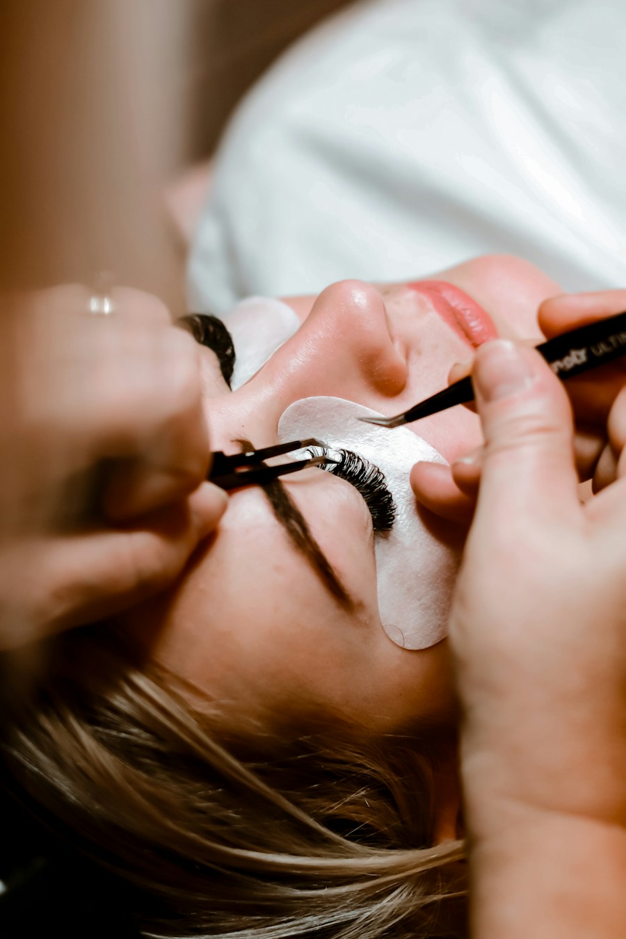 Technician applying lash extensions with tweezers